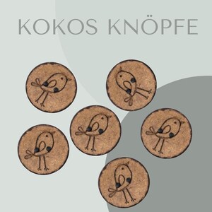 Könnte beinhalten: Sechs runde, naturfarbene Knöpfe mit Vogelmotiv. Jeder Knopf hat einen dunkelbraunen Umriss und eine einfache Illustration eines Vogels mit schwarzem Auge und Flügel. Der Text "KOKOS KNÖPFE" steht oben.