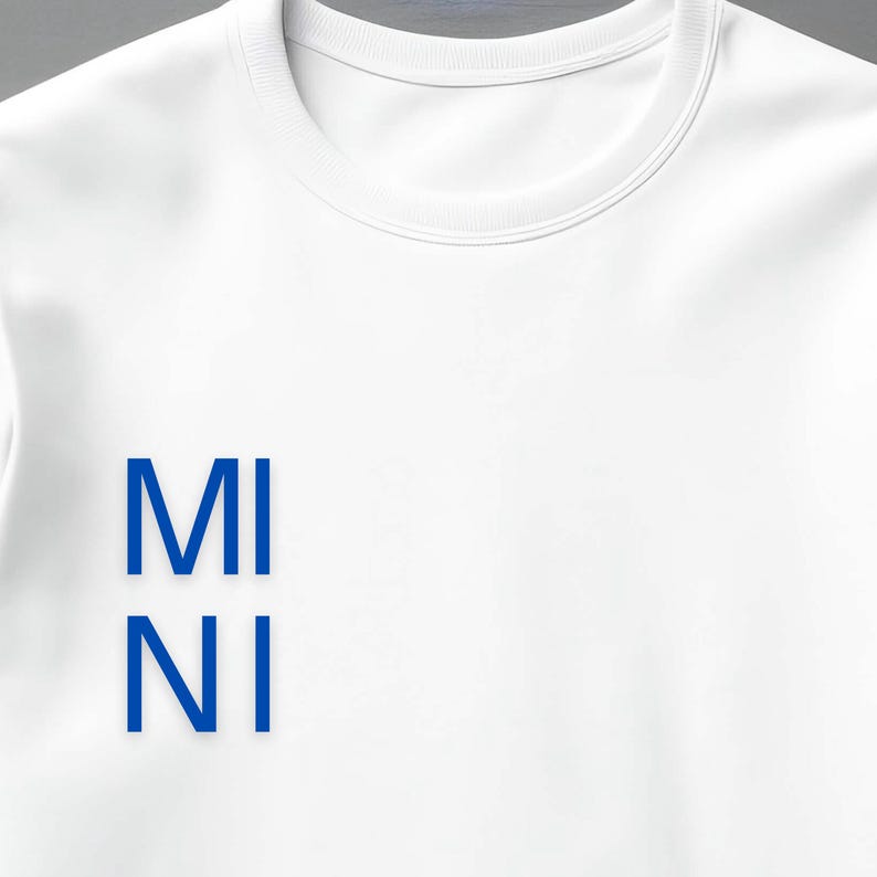Puede incluir: Sudadera blanca de cuello redondo con el texto azul "MI NI" alineado verticalmente en la parte delantera. La sudadera tiene un dise&ntilde;o cl&aacute;sico y minimalista, adecuado para ropa casual. La tela parece suave y c&oacute;moda.
