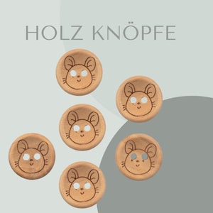 May include: Six wooden buttons with a mouse design. The buttons are light brown and have a white outline around the mouse design. The text "HOLZ KNÖPFE" is printed in black at the top of the image.