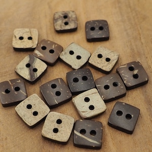 May include: A collection of brown and beige coconut shell buttons with two holes each. The buttons are square shaped and have a natural, rustic look.