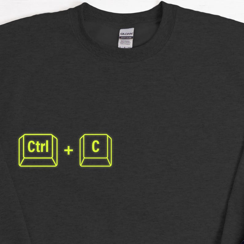 Może przedstawiać: Czarna bluza z neonowo-ż&oacute;łtą grafiką skr&oacute;tu klawiaturowego "Ctrl + C". Tekst i symbole są zamknięte w kwadratowym obrysie. Widoczna jest metka marki Gildan.