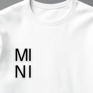 Puede incluir: Sudadera blanca de cuello redondo con las letras negras "MI" sobre "NI". La sudadera est&aacute; hecha de un material suave y tiene un estilo cl&aacute;sico e informal. El dise&ntilde;o es simple y moderno.