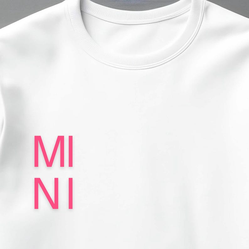 Puede incluir: Sudadera blanca de cuello redondo con la palabra "MINI" impresa verticalmente en letras rosa brillante en la parte delantera. La sudadera tiene un dise&ntilde;o cl&aacute;sico e informal, adecuado para el uso diario.