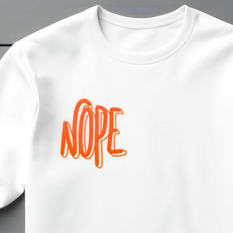 Op de afbeelding: Wit T-shirt met het woord "NOPE" in oranje op de voorkant.