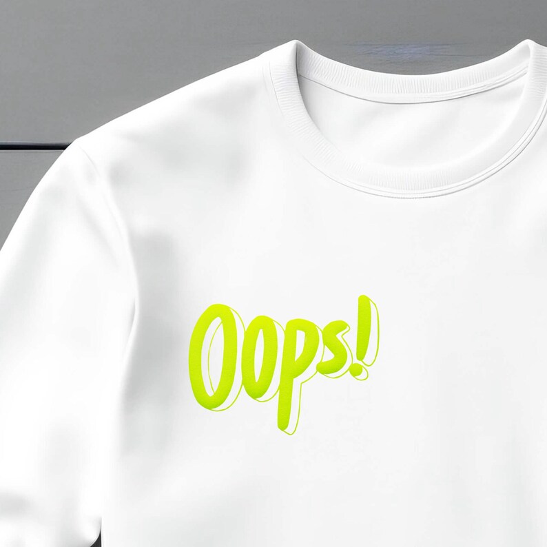 May include: White sweatshirt with a neon green "Oops!" graphic printed on the front.