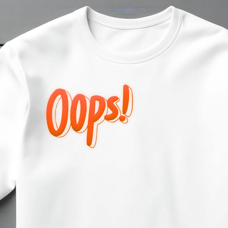 May include: White t-shirt with the word "Oops!" printed in orange on the front.