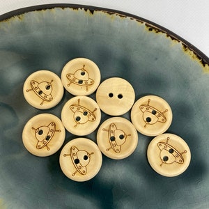 Könnte beinhalten: Zehn braune Holz-Knöpfe mit einem lasergravierten Design eines UFOs. Die Knöpfe haben jeweils zwei Löcher.