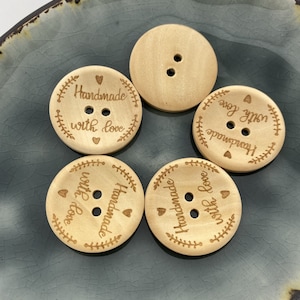 May include: Five wooden buttons with the text "Handmade with love" engraved on them. The buttons are light brown and have two holes each.