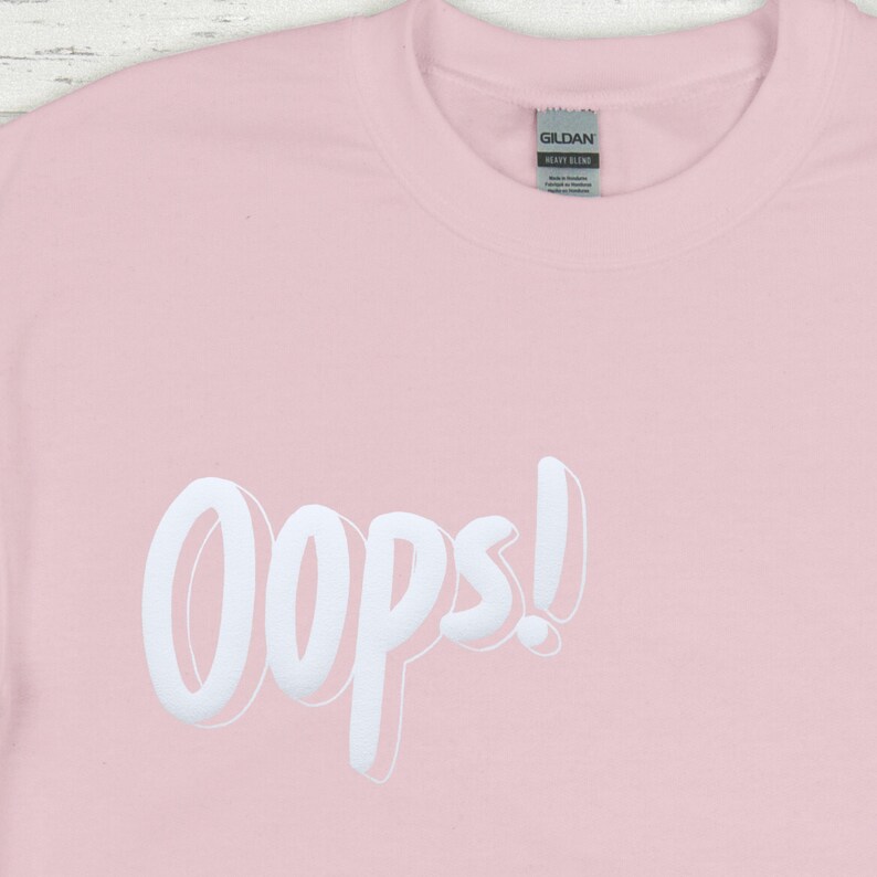 May include: A pink t-shirt with the word "Oops!" printed in white on the front.