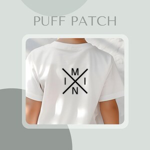 May include: White t-shirt with a black graphic on the back. The design includes the letters "M", "I", and "N" in a crossed-out pattern. The text "PUFF PATCH" is displayed above the t-shirt.