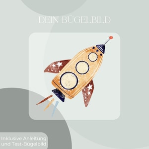 Könnte beinhalten: Eine Illustration einer Rakete in Orange, Braun und Blau mit weißen Sternen auf den Flügeln. Der Text "DEIN BÜGELBILD" steht oben und "Inklusive Anleitung und Test-Bügelbild" steht unten.