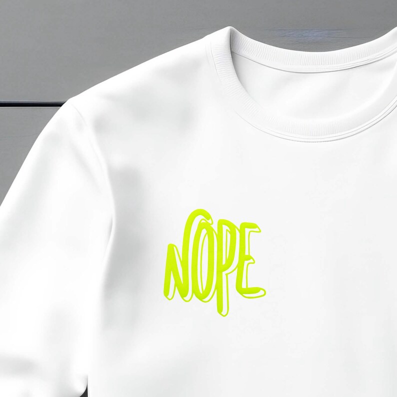 Op de afbeelding: Witte longsleeve met een neon groene grafische afbeelding met de tekst "NOPE" in een vet, gestileerd lettertype.
