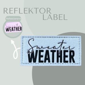 Könnte beinhalten: Ein rechteckiger, hellblauer Bügel-Patch mit einem weißen, gestickten Rand. Der Patch trägt die Aufschrift "Sweater Weather" in schwarzer Schrift mit einem kursiv geschriebenen "Sweater" und einem fetten "WEATHER".