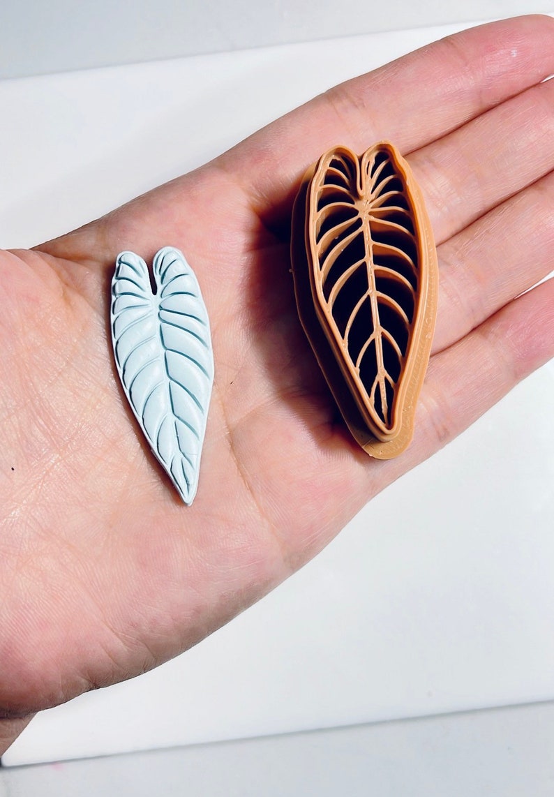 Puede incluir: Un par de moldes de silicona en forma de hoja. Un molde es azul claro y el otro es marr&oacute;n. Los moldes est&aacute;n dise&ntilde;ados para crear decoraciones en forma de hoja.