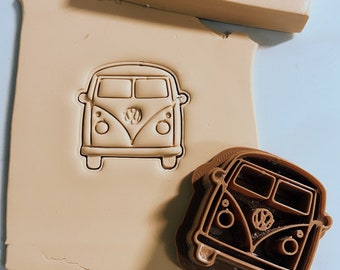 Puede incluir: Un cortador de galletas de plástico marrón con forma de furgoneta Volkswagen vintage. El cortador está sobre una superficie beige con una impresión marrón de la furgoneta.