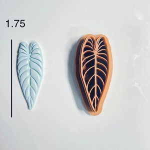 Puede incluir: Un cortador de galletas en forma de hoja de color azul claro con un cortador de galletas en forma de hoja de color marr&oacute;n a su lado. Los cortadores de galletas tienen 1,75 pulgadas de alto.