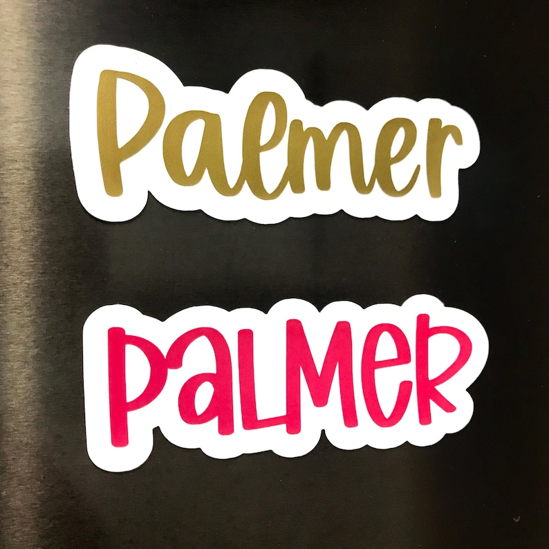 May include: Two stickers with the name "Palmer" in a playful font. One sticker has gold lettering, and the other has pink lettering. Both stickers have a white border and are on a black background.