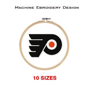 Op de afbeelding: Machine borduurontwerp van het logo van de Philadelphia Flyers. Het logo is zwart en oranje met een witte omtrek. Het logo wordt weergegeven op een witte achtergrond in een houten borduurring. De tekst "10 MATEN" wordt onder de ring weergegeven.