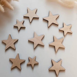May include: A set of ten wooden stars in various sizes, all with a natural wood finish. The stars are arranged in a circle on a white background.