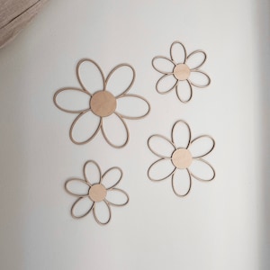 May include: Four wooden daisy shapes in various sizes, painted in a light wood tone. The daisies are arranged on a white background.