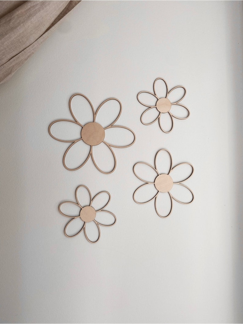May include: Four wooden daisy shapes in various sizes, painted in a light wood tone. The daisies are arranged on a white background.