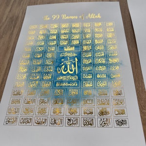 Puede incluir: Un póster blanco con un fondo de acuarela azul y letras doradas. El póster presenta los 99 nombres de Alá en escritura árabe, con la palabra "Alá" en una fuente más grande en el centro. El título "The 99 Names of Allah" está en la parte superior del póster.