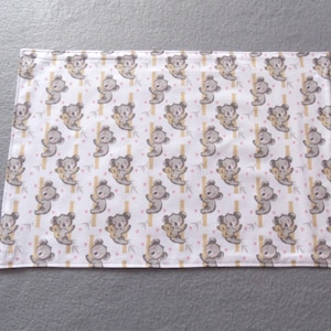 Könnte beinhalten: Weiße Babydecke mit einem sich wiederholenden Muster aus grauen Koalas, die ein kleines gelbes Koala halten, rosa Herzen und braunen Bambusstangen.