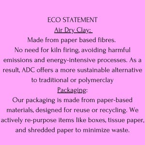May include: A pink background with text detailing the eco-friendly aspects of Air Dry Clay. The text highlights the use of paper-based fibers, no kiln firing, and sustainable packaging made from recycled materials.