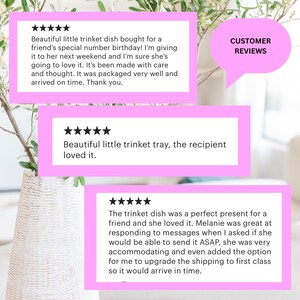 May include: Image features customer reviews in pink boxes with white text. The reviews praise a trinket dish, highlighting its quality and suitability as a gift. The text includes phrases like "Beautiful trinket dish" and "the recipient loved it."