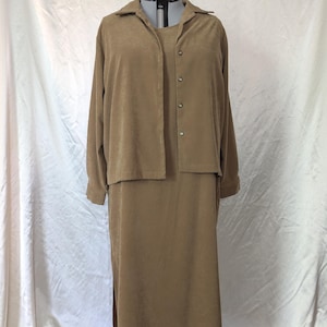 May include: A tan two-piece set consisting of a long-sleeved button-down shirt with a collar and a matching sleeveless midi-length dress. The fabric has a soft, suede-like texture, and the shirt features four visible buttons down the front.