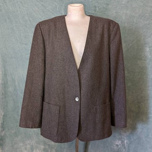 May include: A gray blazer with a single button closure and two pockets. The blazer has a v-neck and is made of a textured fabric.