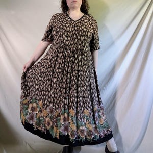 May include: A vintage V-neck dress with a black and brown animal print pattern. The dress features short sleeves and a full skirt with a floral border in shades of yellow, purple, and green. The dress is knee-length.