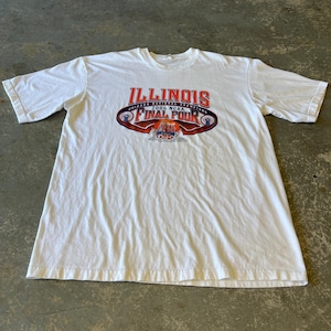 May include: White t-shirt featuring the text "ILLINOIS" in orange and the words "FINAL FOUR" in blue and orange. The shirt commemorates the 2005 NCAA Chicago Regional Championships. The shirt is made of a soft, comfortable material.