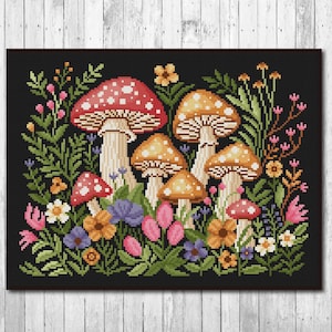 May include: A cross-stitch pattern featuring a cluster of colorful mushrooms with red and white caps, surrounded by green leaves and pink, yellow, and purple flowers on a black background.
