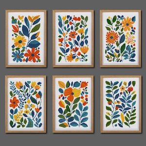 Pode incluir: Seis impressões de arte floral emolduradas. Cada impressão apresenta um design colorido de ponto cruz de flores e folhas em tons de laranja, amarelo, azul e verde. As molduras são de madeira castanha clara.
