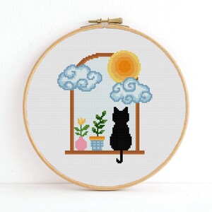 May include: Cross stitch pattern featuring a black cat sitting in a window with a yellow sun, clouds, and potted plants.