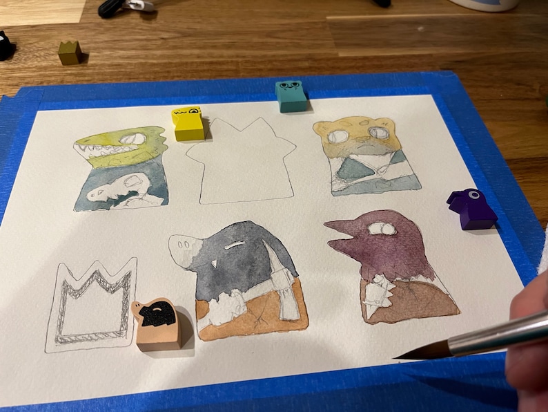 May include: A watercolor painting of various animal characters on a white background. The characters include a crocodile, a cheetah, a bird, a pig, and a house. The painting is surrounded by blue painter's tape.
