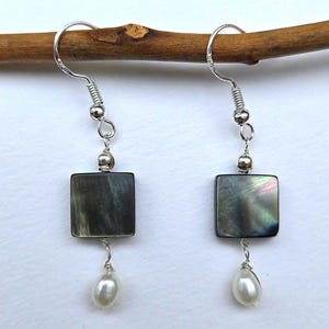 May include: A pair of silver earrings with a square iridescent black shell pendant and a white pearl dangling below.