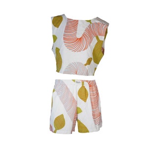 Könnte beinhalten: Ein weißes Crop-Top und passende Shorts mit einem farbenfrohen abstrakten Druck aus orangefarbenen, grünen und rosafarbenen Linien und Formen.