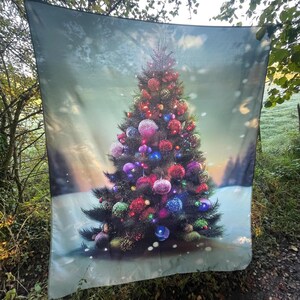 May include: A festive Christmas tree tapestry, adorned with vibrant baubles and lights, set against a snowy backdrop. The fabric is displayed outdoors, creating a seasonal scene. The image shows a winter landscape.