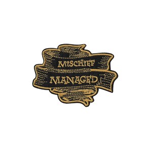 Può includere: Una toppa ricamata raffigurante un nastro nero con bordi e scritte color oro. Il testo recita MISCHIEF sulla riga superiore e MANAGED sulla riga inferiore, entrambi in un carattere serif, su uno sfondo nero.