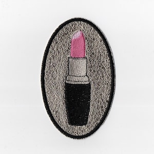 Peut inclure: Écusson brodé représentant un rouge à lèvres rose avec un tube argenté et une base noire. Le rouge à lèvres est placé sur un fond ovale texturé avec une bordure noire. Le patch est conçu pour être appliqué sur des vêtements ou des accessoires.