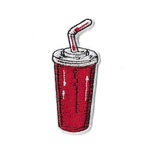 Peut inclure: Un écusson brodé représentant un gobelet de soda rouge avec un couvercle blanc et une paille coudée. Le motif utilise des contours et des détails en fil noir, avec des reflets blancs sur le gobelet et la paille, créant un aspect texturé.