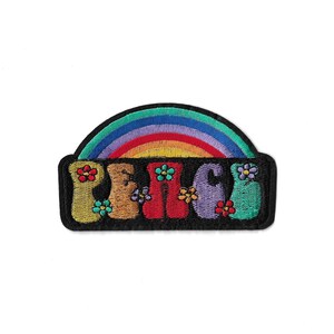 Op de afbeelding: Een geborduurde patch met een regenboogboog boven het woord PEACE in grote, kleurrijke letters in bubbelstijl. De letters zijn geel, beige, rood, paars en blauwgroen, versierd met kleine, veelkleurige geborduurde bloemen.