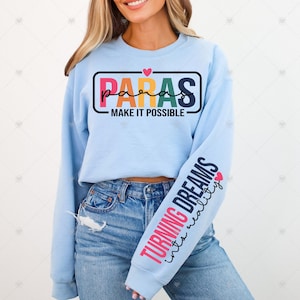 May include: A light blue sweatshirt with the text "PARAS MAKE IT POSSIBLE" in a rainbow color scheme on the front and the text "TURNING DREAMS into reality" on the sleeve.