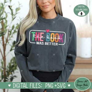 May include: A dark gray long-sleeved shirt with a colorful graphic that says "THE BOOK WAS BETTER" with a small red heart above the text.