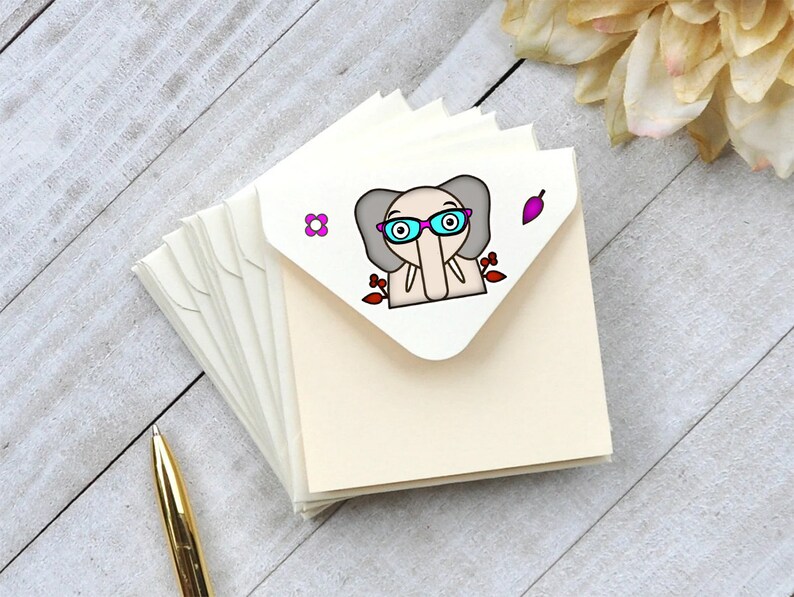 May include: A stack of ivory note cards with a cute cartoon elephant wearing pink glasses and a red flower on the front.