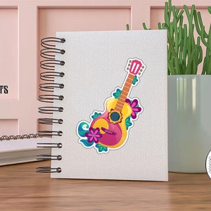 May include: A colorful sticker of a pink and yellow guitar with floral designs. The sticker is on a white notebook with a black spiral binding. The text "Colorful Stickers for Your Projects" is on the pink wall behind the notebook.