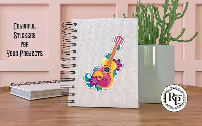 May include: A colorful sticker of a pink and yellow guitar with floral designs. The sticker is on a white notebook with a black spiral binding. The text "Colorful Stickers for Your Projects" is on the pink wall behind the notebook.