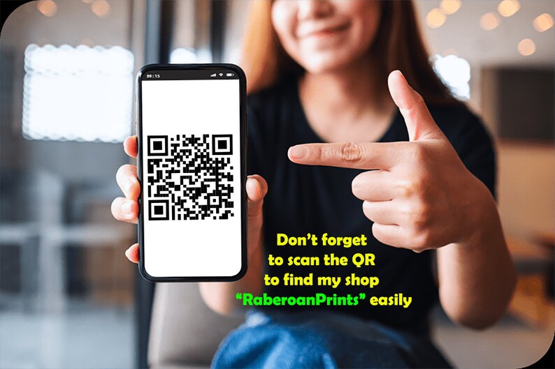 May include: A person holding a smartphone displaying a QR code. The text on the screen reads "Don't forget to scan the QR to find my shop "RaberoanPrints" easily."